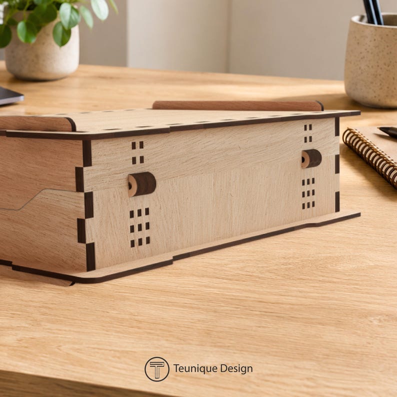 May include: A light-coloured wooden box with a lid and a handle. The box has a rectangular shape with decorative cutouts and a dovetail joint design. The text "Teunique Design" is printed on the bottom.