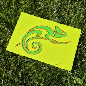 Könnte beinhalten: Ein rechteckiges, neongelbes Schild mit einer stilisierten, abstrakten Grafik eines Chamäleons. Das Design besteht aus hellgrünen Linien mit dünnen orangefarbenen Umrandungen, die eine geschichtete, fließende Form des gekrümmten Körpers bilden.