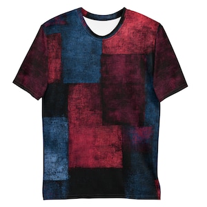 May include: A short-sleeved t-shirt with a geometric design. The shirt features a patchwork pattern of red, blue, and black squares. The fabric has a textured appearance, giving it a unique, artistic look. The shirt has a crew neck and a relaxed fit.