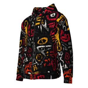 Puede incluir: Sudadera con capucha negra con cremallera y un patrón abstracto vibrante. El diseño presenta formas y símbolos rojos, amarillos, blancos y grises sobre un fondo negro. La sudadera tiene capucha y cremallera completa.