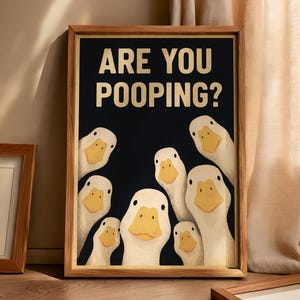 a framed poster with a humorous cartoon duck illustration, displaying the text "ARE YOU POOPING?"