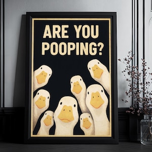 A framed poster with a humorous cartoon duck illustration, displaying the text "ARE YOU POOPING?"