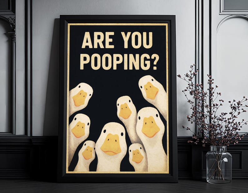 A framed poster with a humorous cartoon duck illustration, displaying the text "ARE YOU POOPING?"