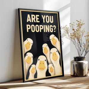 A framed poster with a cartoon image of ducks and the text "ARE YOU POOPING?"