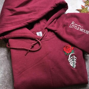 a red hoodie with a rose embroidered on it