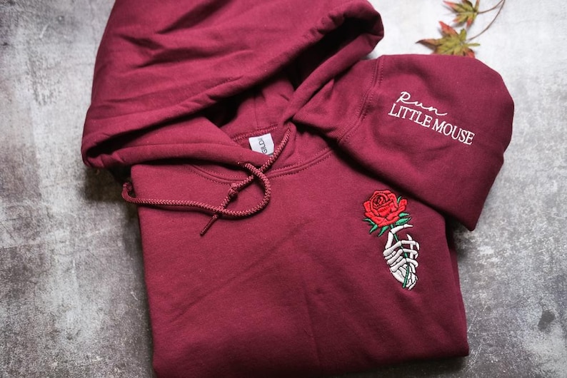 a red hoodie with a rose embroidered on it