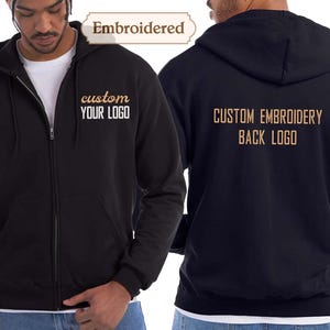 May include: Black zip-up hoodie with the text "custom YOUR LOGO" embroidered on the front. The back of the hoodie features the text "CUSTOM EMBROIDERY BACK LOGO". The hoodie is shown on a person.