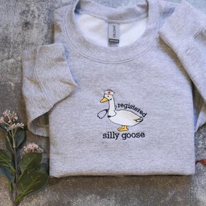 a gray sweatshirt with a cartoon duck and the text "regulated silly goose" printed on it.