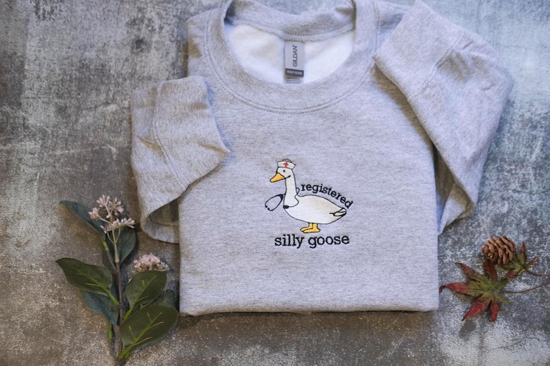 a gray sweatshirt with a cartoon duck and the text "regulated silly goose" printed on it.