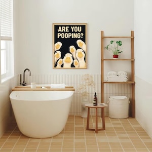 a bathroom with a large white bathtub, a framed poster of ducks, a shelf with a plant, and a small table.