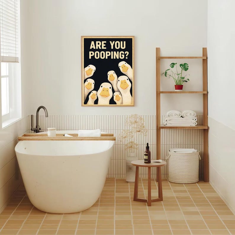 a bathroom with a large white bathtub, a framed poster of ducks, a shelf with a plant, and a small table.