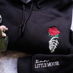 a black hoodie with a rose embroidered on it