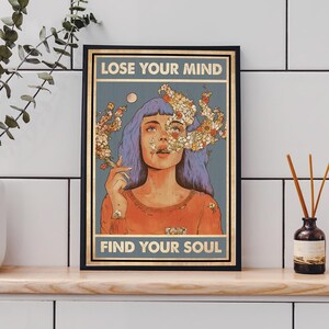 May include: Framed art print featuring a woman with blue hair and floral elements, holding a cigarette. The text reads "LOSE YOUR MIND" at the top and "FIND YOUR SOUL" at the bottom, set against a blue background.