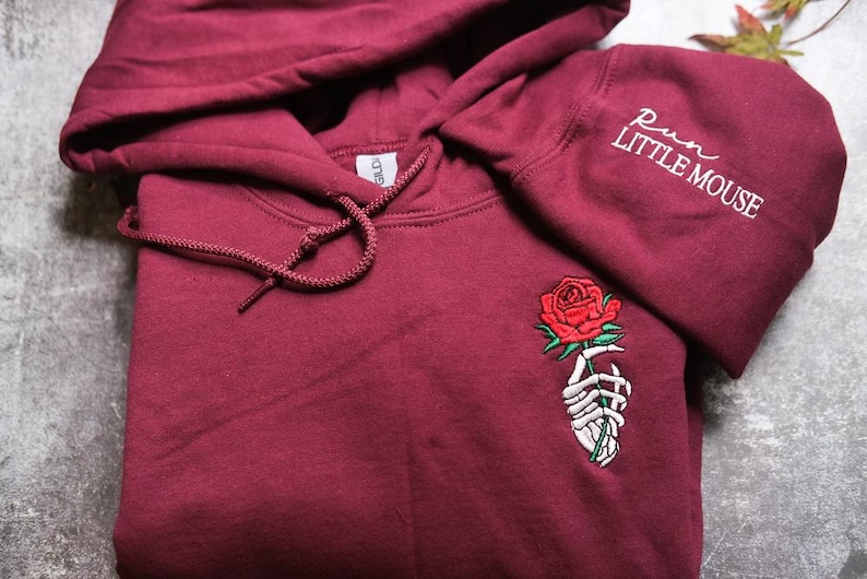a red hoodie with a rose embroidered on it