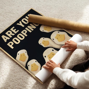 A person is rolling up a poster with a humorous message about ducks.