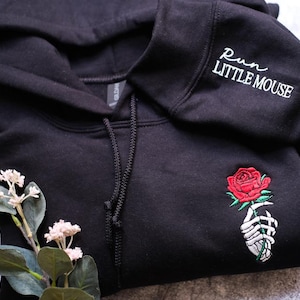 a black sweatshirt with a rose embroidered on it