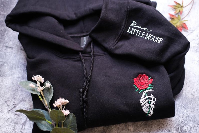 a black sweatshirt with a rose embroidered on it