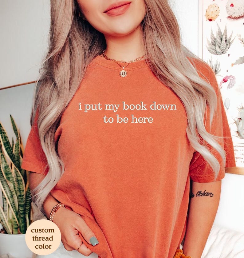 a woman wearing a t - shirt that says i put my book down to be