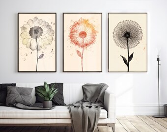 Op de afbeelding: Drie ingelijste aquarellen van paardenbloemen. De eerste aquarel is in grijstinten en wit, de tweede is in oranje en rood, en de derde is in zwart en wit.