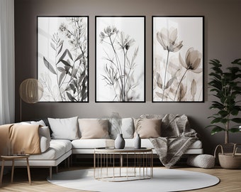 May include: Three black and white framed prints of botanical illustrations with a white background. The prints are hanging on a brown wall above a white sectional sofa with brown throw pillows and a blanket. There is a gold metal coffee table in front of the sofa.