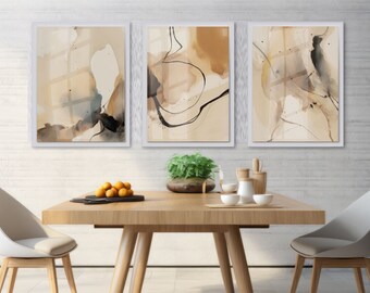 Könnte beinhalten: Drei abstrakte Kunstdrucke in weißen Rahmen mit braunen, beigefarbenen und schwarzen aquarellartigen Designs. Die Drucke hängen an einer weißen Backsteinwand über einem Holztisch mit zwei Stühlen.