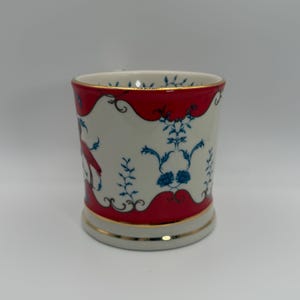 May include: A set of three ceramic mugs with a speckled, matte finish. The mugs are in shades of cream, light gray, and dark gray. Each mug has a simple, minimalist design and a rounded handle.