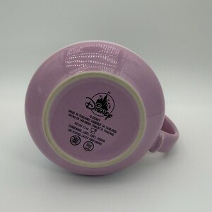 Puede incluir: Una taza de cer&aacute;mica de color lavanda con asa. La base de la taza muestra el logotipo de Disney y texto que indica que contiene 425 ml y est&aacute; hecha de gres en Tailandia.