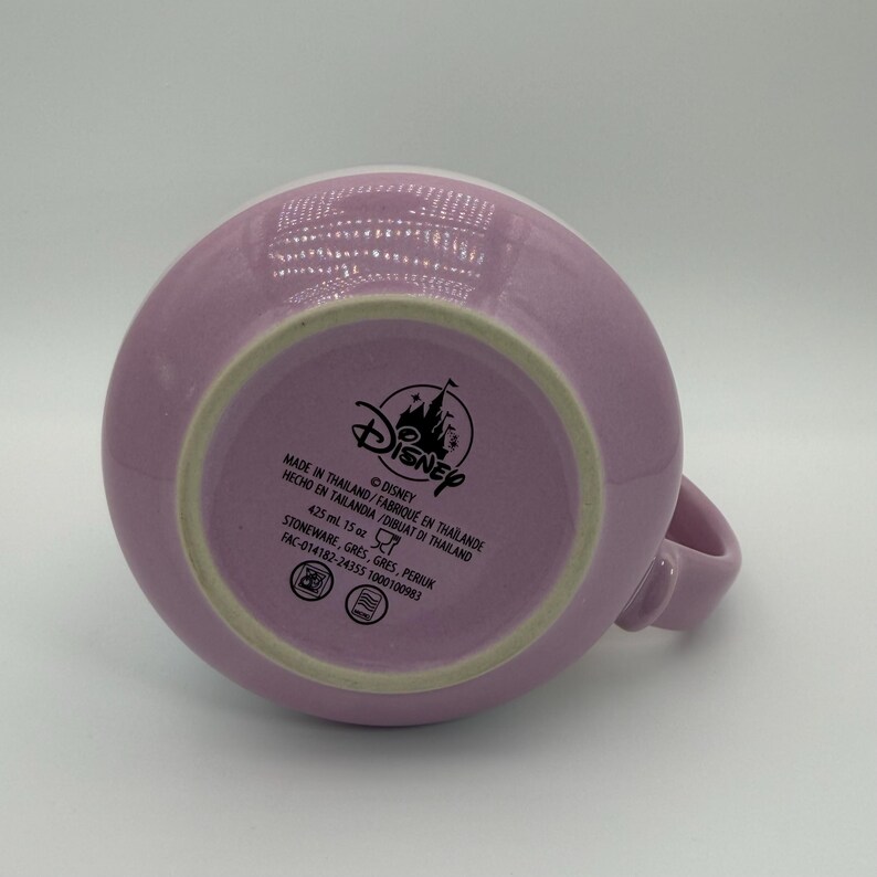Puede incluir: Una taza de cer&aacute;mica de color lavanda con asa. La base de la taza muestra el logotipo de Disney y texto que indica que contiene 425 ml y est&aacute; hecha de gres en Tailandia.