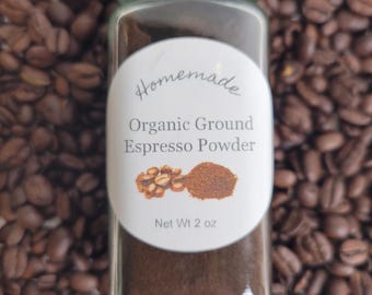 Puede incluir: Un frasco de vidrio lleno de polvo de espresso marrón oscuro. El frasco tiene una etiqueta blanca que dice "Homemade Organic Ground Espresso Powder" y "Net Wt 2 oz". El frasco está rodeado de granos de café.