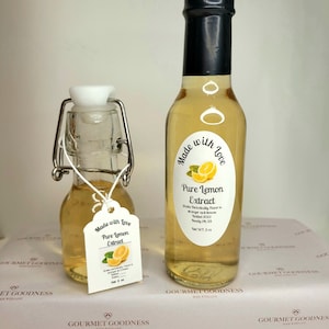May include: Two glass bottles of pure lemon extract, both with black labels that say "Made with Love" and "Pure Lemon Extract". The smaller bottle has a white label with the same text. The larger bottle is 6 oz.