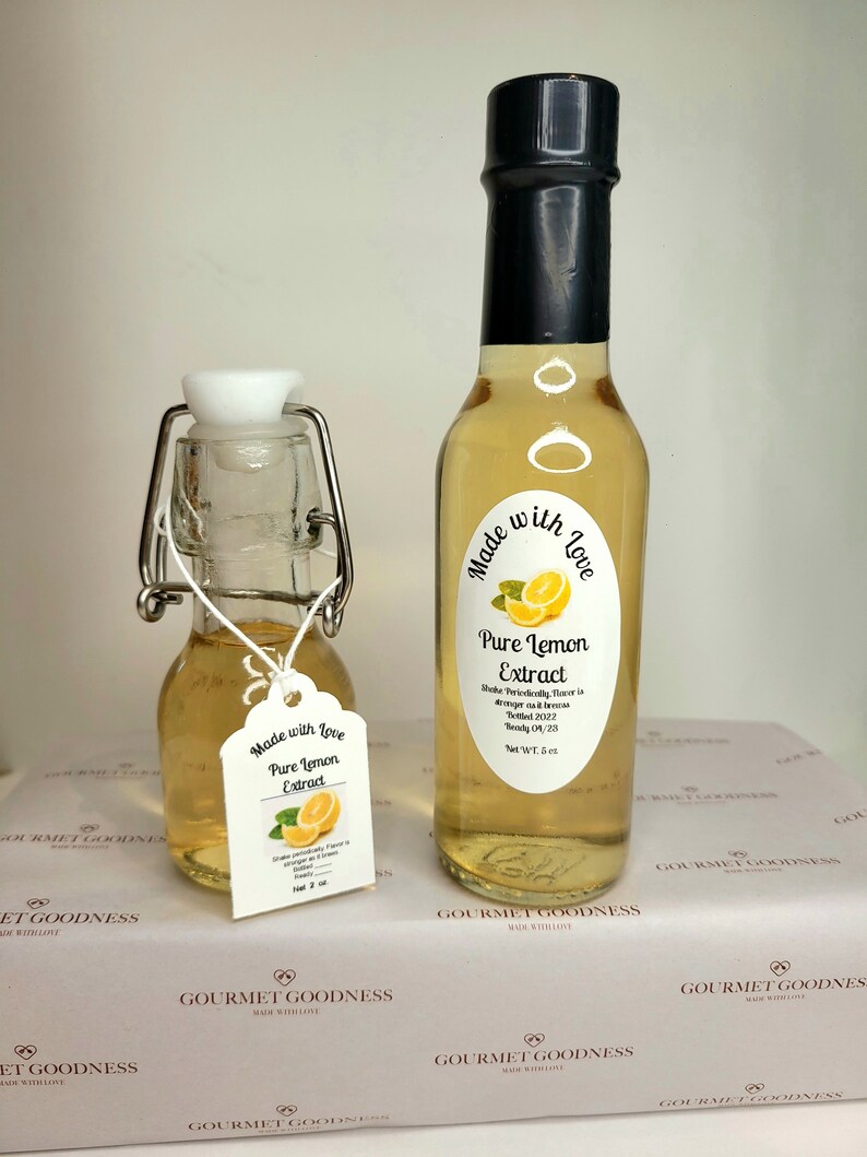 May include: Two glass bottles of pure lemon extract, both with black labels that say "Made with Love" and "Pure Lemon Extract". The smaller bottle has a white label with the same text. The larger bottle is 6 oz.