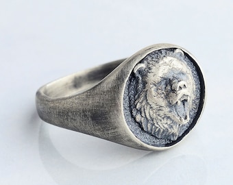 Könnte beinhalten: Ein silberner Ring mit einem detaillierten Bärenkopfdesign. Der Ring hat eine strukturierte, gealterte Oberfläche.