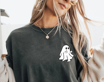 May include: A dark gray long-sleeved t-shirt with a white ghost graphic on the left chest. The ghost has two eyes and a small smile.