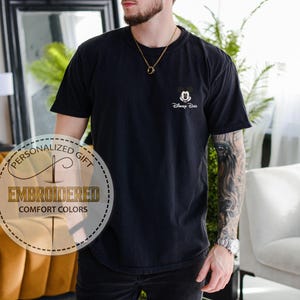 May include: Black t-shirt with a small embroidered Mickey Mouse design and the text "Disney Duo". The shirt also has a circular graphic that says "Personalized Gift" and "Embroidered Comfort Colors".