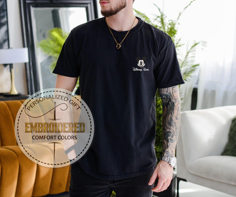 May include: Black t-shirt with a small embroidered Mickey Mouse design and the text "Disney Duo". The shirt also has a circular graphic that says "Personalized Gift" and "Embroidered Comfort Colors".