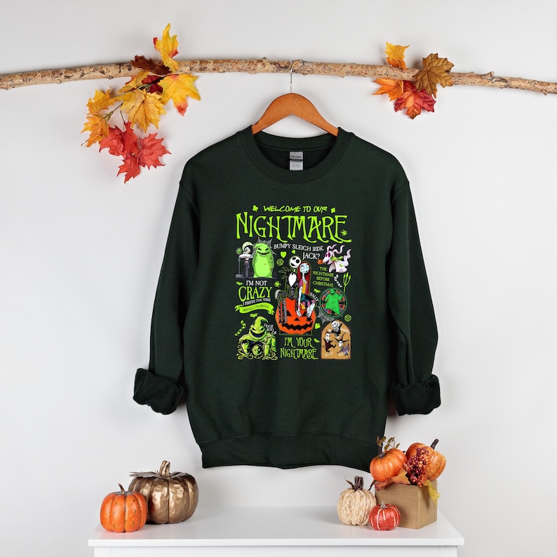 May include: Dark green sweatshirt with a graphic featuring characters and text from "The Nightmare Before Christmas." The design includes the words "Welcome to our Nightmare" and "I'm not crazy, I'm your nightmare."