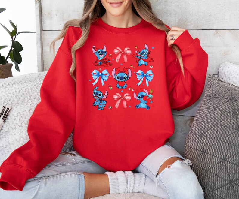 K&ouml;nnte beinhalten: Roter Pullover mit einem sich wiederholenden Muster aus blauen Stitch-Figuren, die Schleifen tragen. Stitch ist eine Zeichentrickfigur aus dem Disney-Film Lilo & Stitch.