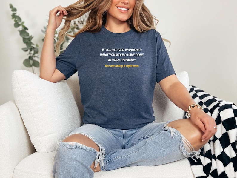 May include: A navy blue t-shirt with white text that reads "IF YOU'VE EVER WONDERED WHAT YOU WOULD HAVE DONE IN 1930s GERMANY: You are doing it right now."