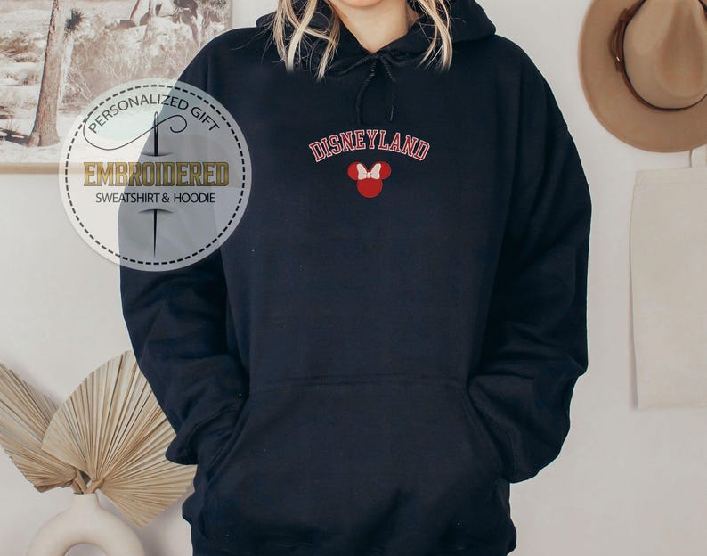 May include: Black hooded sweatshirt with the text "DISNEYLAND" in red and white lettering and a red Mickey Mouse head with a white bow on the front.