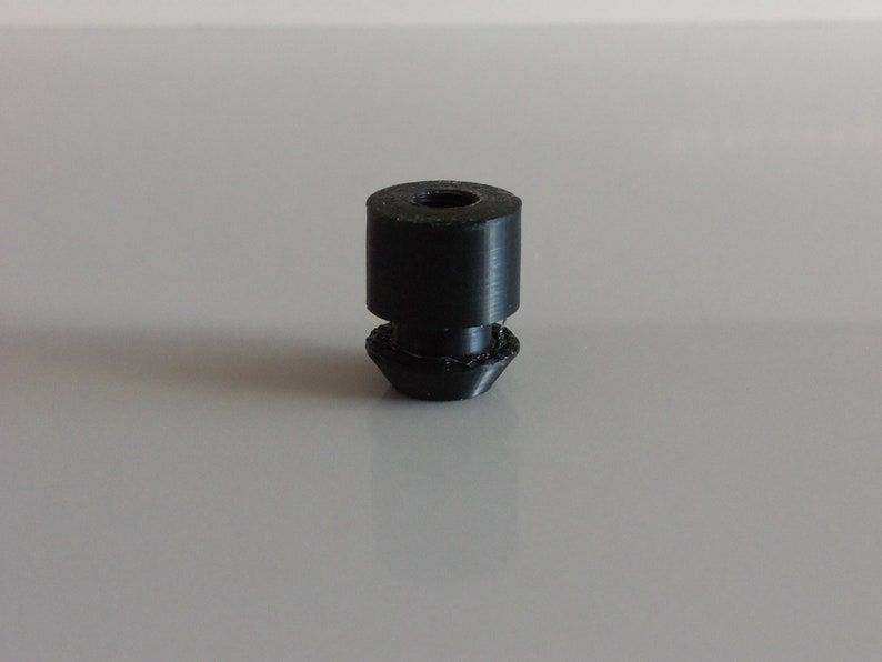 May include: A black rubber furniture leg with a threaded top and a rounded bottom.