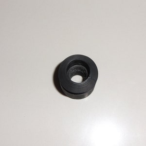 May include: A black rubber grommet with a circular hole in the center.