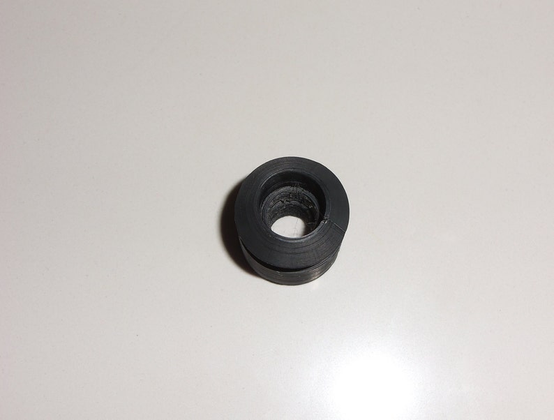 May include: A black rubber grommet with a circular hole in the center.