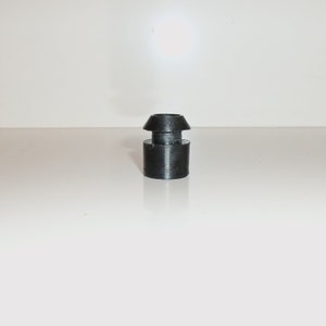 Puede incluir: Un tapón de botella de goma negra con una parte superior acampanada.