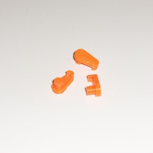 May include: Three orange plastic pieces, possibly for a toy or model kit.