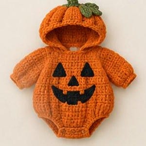 May include: An orange crocheted long-sleeve romper featuring a hood with a green leaf accent. The front displays a black jack-o'-lantern face with two triangular eyes and a wide, toothy grin. The garment has a ribbed texture and snap closures.