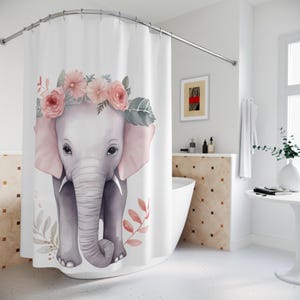 May include: A white shower curtain with a watercolor illustration of a gray elephant wearing a pink flower crown. The elephant is standing on a white background with pink and green floral accents.
