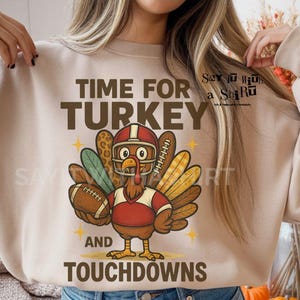 May include: Beige sweatshirt with a cartoon turkey wearing a football helmet and holding a football. The text "TIME FOR TURKEY AND TOUCHDOWNS" is above and below the turkey graphic. The words "DIGITAL DOWNLOAD - 300 DPI - PNG FILE" are at the bottom.
