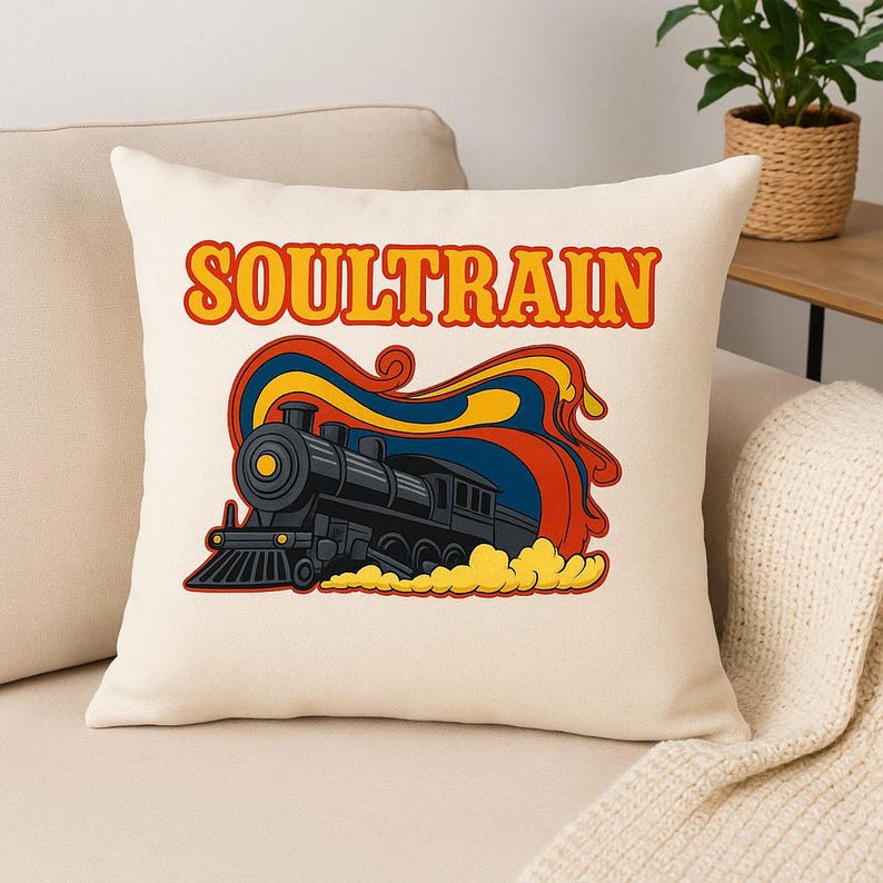 May include: Cream-colored throw pillow featuring a retro illustration of a black steam train with the word "SOULTRAIN" in orange and yellow. The train is set against a backdrop of swirling red, blue, and yellow colors, with yellow smoke.