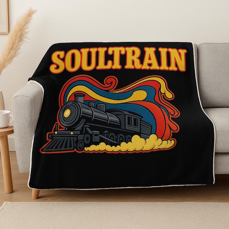 May include: Black throw blanket featuring a retro illustration of a black steam train with the text "SOULTRAIN" in yellow and orange. The design includes red, blue, and yellow swirls, and yellow smoke.