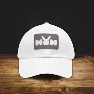 May include: White baseball cap with a gray patch featuring the letters "MYM" with a white bunny rabbit in the middle.